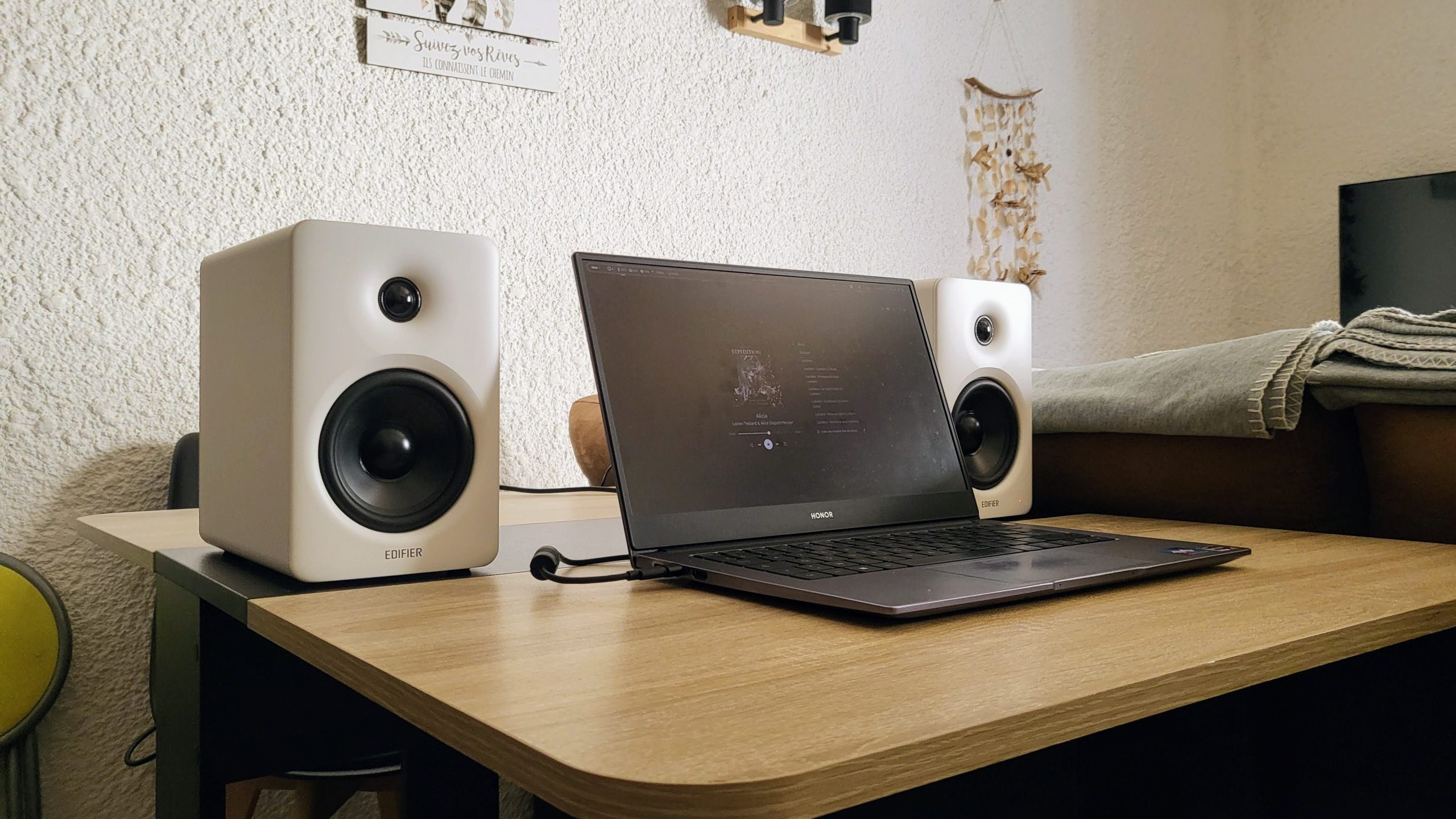 Photo des M90 posées sur une table en bois et branchées à un Pc portable Honor.